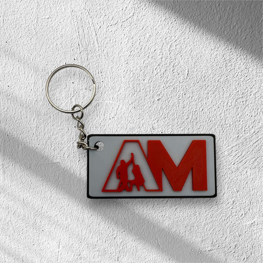 Modern custom logo keychain for businesses featuring red AM letters on white plate